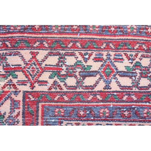 207 - A large decorative Iranian rug of red ground decorated with various geometric patterns, approx 309cm... 