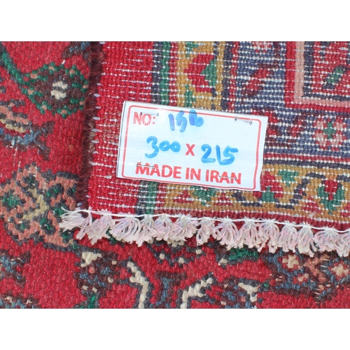 207 - A large decorative Iranian rug of red ground decorated with various geometric patterns, approx 309cm... 