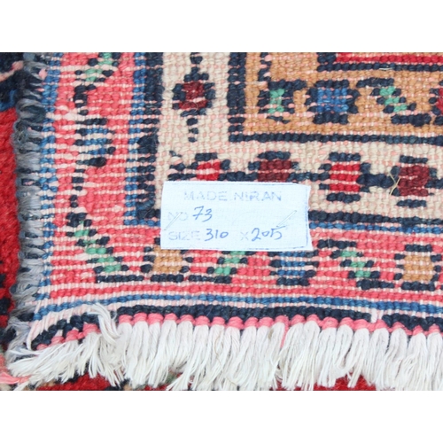 209 - A large decorative Iranian rug of red ground with geometric border, approx 313cm x 200cm, label vers... 