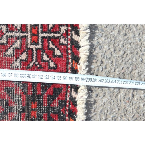 217 - A vintage Iranian made red ground rug decorated with 3 lines of 6 gul, approx 200cm x 124cm, label v... 