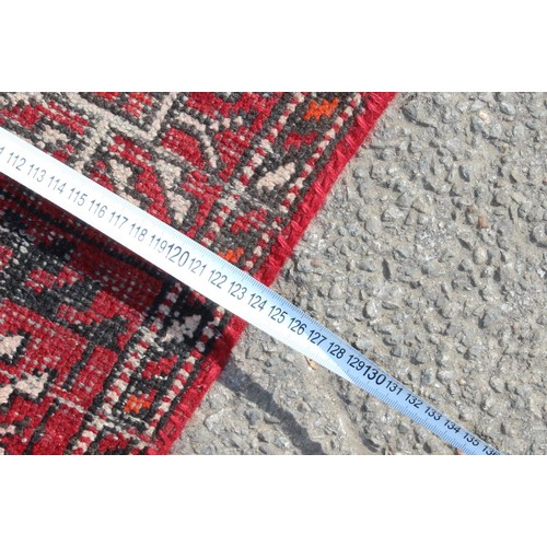217 - A vintage Iranian made red ground rug decorated with 3 lines of 6 gul, approx 200cm x 124cm, label v... 