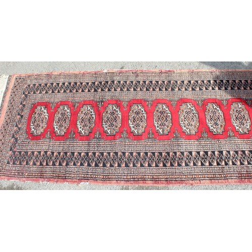 220 - A long vintage hall runner rug of red ground, decorated with gul, approx 525cm x 81cm