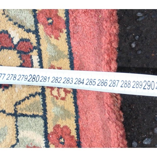 224 - A large decorative rug of red ground with arabesque motifs