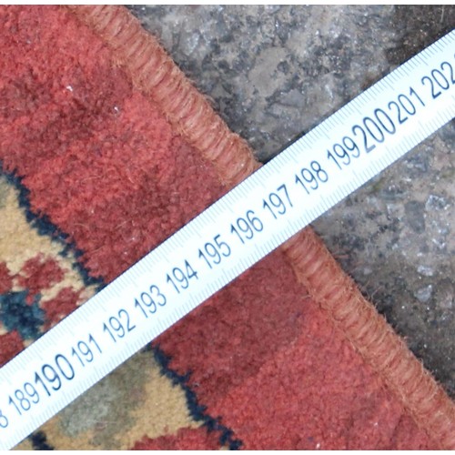 224 - A large decorative rug of red ground with arabesque motifs