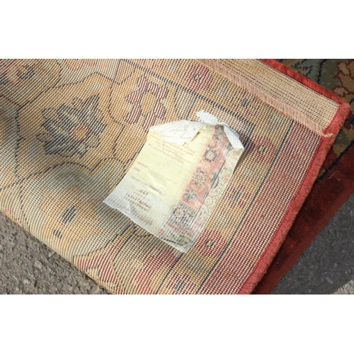 224 - A large decorative rug of red ground with arabesque motifs
