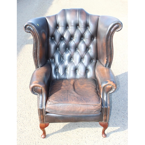 153 - A Georgian style leather brown leather Chesterfield wing back armchair