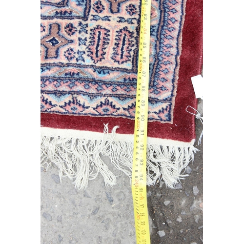 227 - A vintage red ground rug with 3 lines of 7 gul, approx 234cm x 167cm