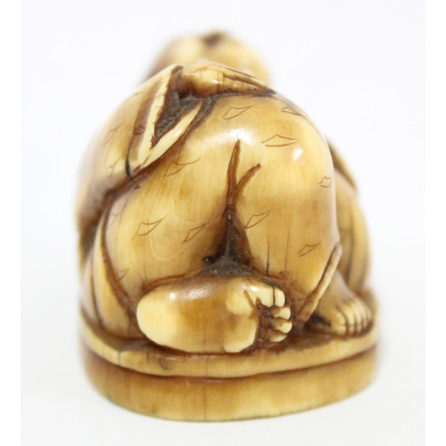 1601 - A Japanese carved netsuke depicting Hotei in laying pose, seemingly unsigned, approx 41mm wide