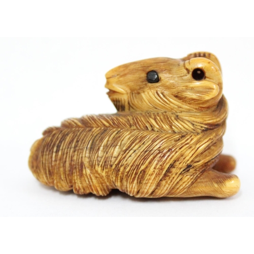 1602 - A Japanese carved netsuke depicting a goat or ram in laying pose, seemingly unsigned, approx 49mm wi... 