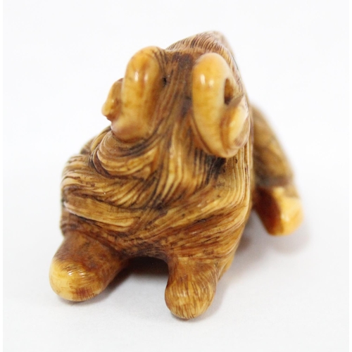 1602 - A Japanese carved netsuke depicting a goat or ram in laying pose, seemingly unsigned, approx 49mm wi... 