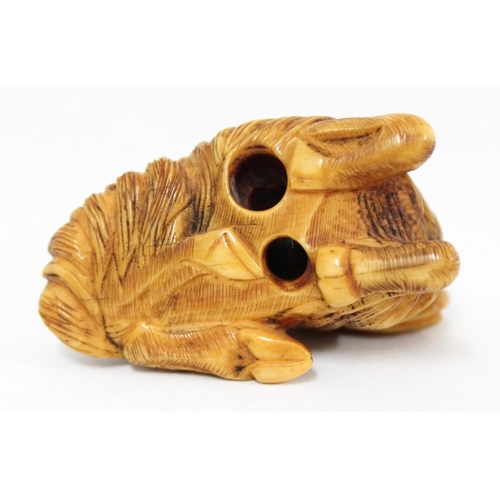 1602 - A Japanese carved netsuke depicting a goat or ram in laying pose, seemingly unsigned, approx 49mm wi... 