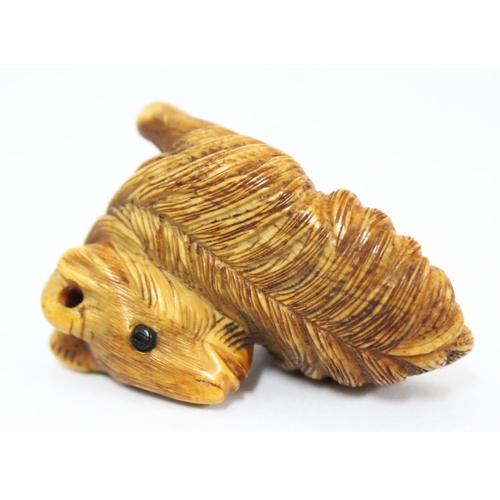 1602 - A Japanese carved netsuke depicting a goat or ram in laying pose, seemingly unsigned, approx 49mm wi... 