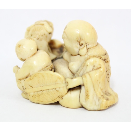 1603 - A Japanese carved netsuke depicting a seated male with 2 playing children, signed, approx 43mm wide