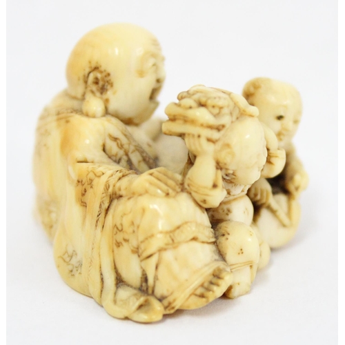 1603 - A Japanese carved netsuke depicting a seated male with 2 playing children, signed, approx 43mm wide