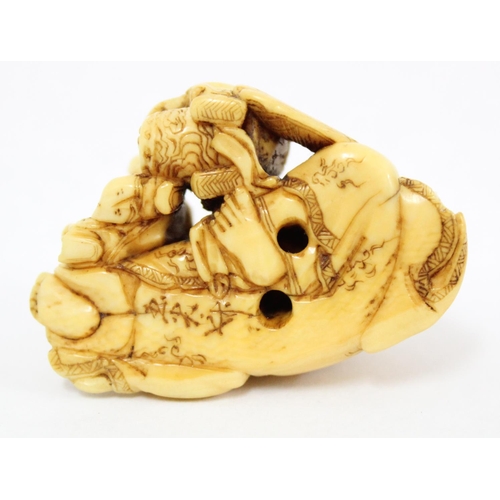 1603 - A Japanese carved netsuke depicting a seated male with 2 playing children, signed, approx 43mm wide