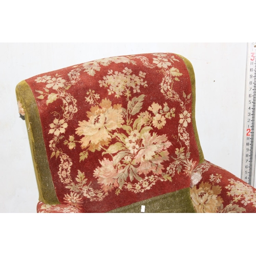 27 - An antique carpet upholstered deep seated armchair on turned wooden legs and metal and ceramic casto... 