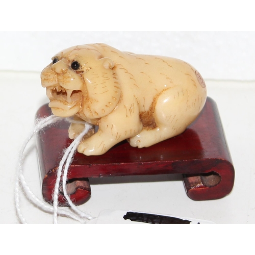 1610a - A Japanese carved figure of a lion, bearing signature to reverse, believed to be a Tagua nut, on woo... 