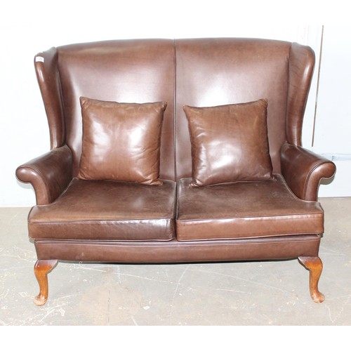 15 - A 20th century brown leather or leatherette wingback 2 seater sofa with 2 cushions