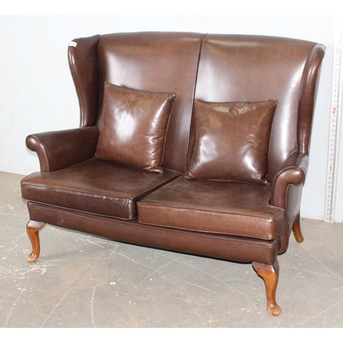 15 - A 20th century brown leather or leatherette wingback 2 seater sofa with 2 cushions