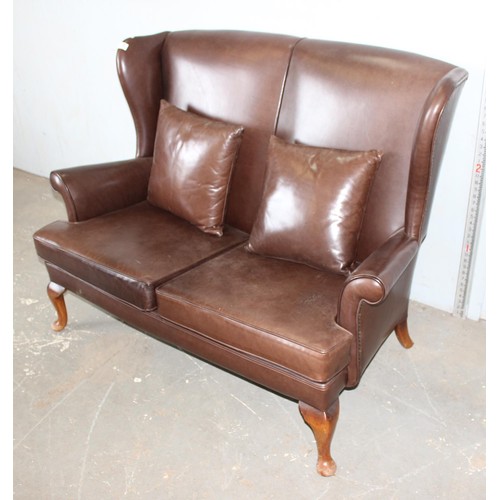 15 - A 20th century brown leather or leatherette wingback 2 seater sofa with 2 cushions