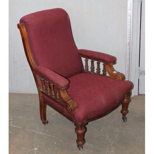 18 - An antique red upholstered armchair with mahogany frame and unusual castors