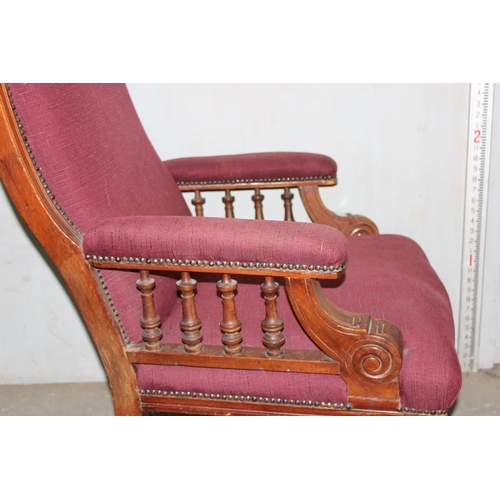 18 - An antique red upholstered armchair with mahogany frame and unusual castors