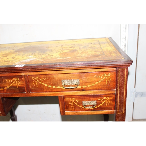 71 - An Edwardian Sheraton revival leather topped desk of small proportions with brass castors