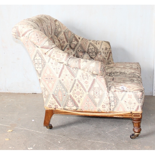 28 - An antique low armchair standing on turned wooden legs with brass and ceramic castors