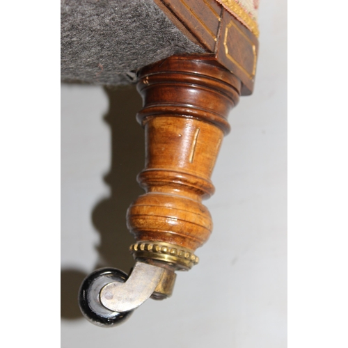 28 - An antique low armchair standing on turned wooden legs with brass and ceramic castors