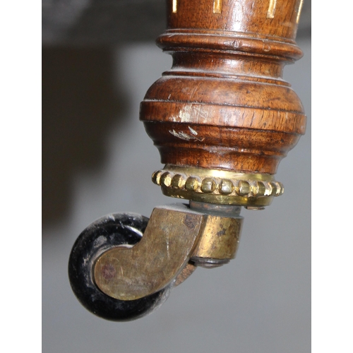 28 - An antique low armchair standing on turned wooden legs with brass and ceramic castors