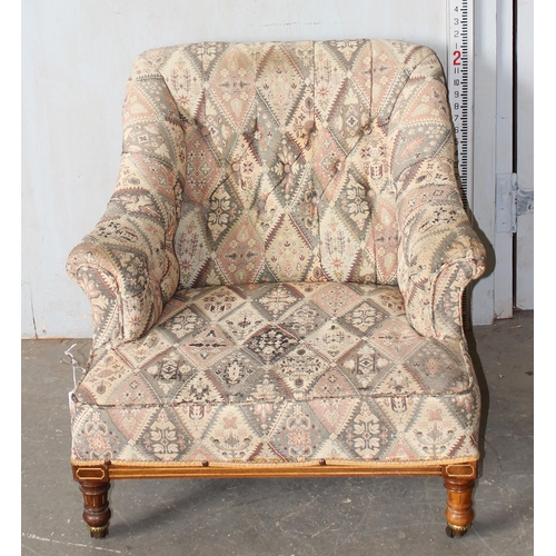 28 - An antique low armchair standing on turned wooden legs with brass and ceramic castors