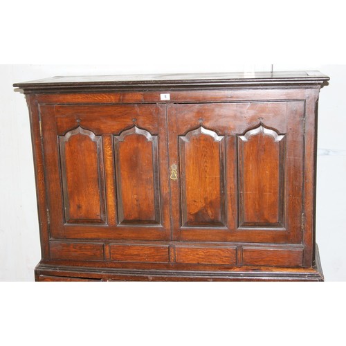 8 - An 18th century oak cabinet, enclosed by two arched panelled doors, the lower section with five draw... 