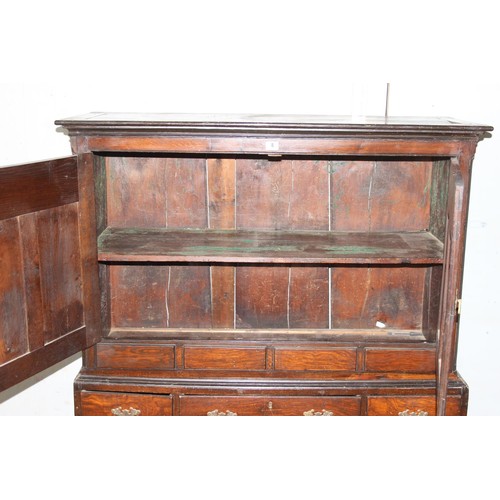 8 - An 18th century oak cabinet, enclosed by two arched panelled doors, the lower section with five draw... 