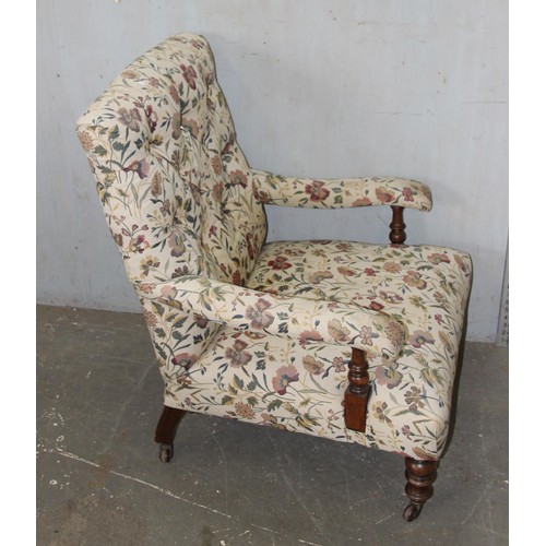 22 - An antique upholstered low armchair with floral upholstery standing on turned wooden legs with brass... 