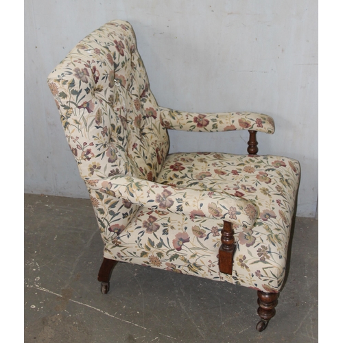 22 - An antique upholstered low armchair with floral upholstery standing on turned wooden legs with brass... 