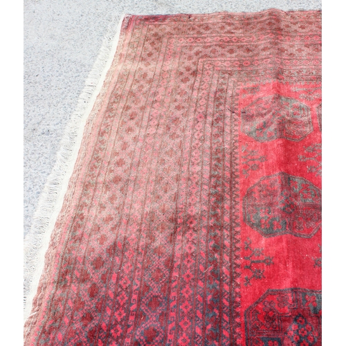 209 - A large hand made Afghan rug of red ground decorated with 3 lines of 7 elephant foot gul, approx 370... 