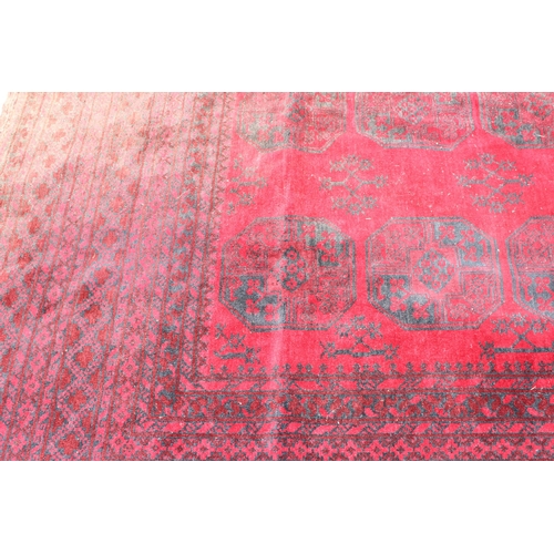 209 - A large hand made Afghan rug of red ground decorated with 3 lines of 7 elephant foot gul, approx 370... 