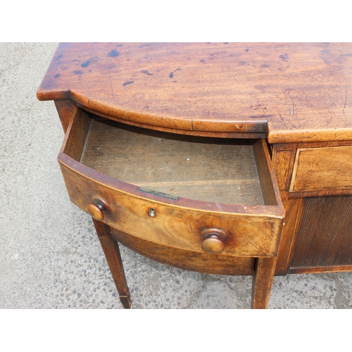 99 - An early 19th century tambour fronted mahogany sideboard of serpentine front with single drawer abov... 