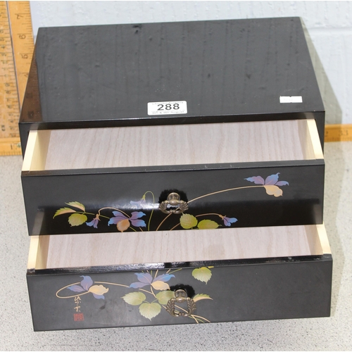 288 - Oriental small two drawer wooden black lacquer cabinet with hand painted floral design to front with... 