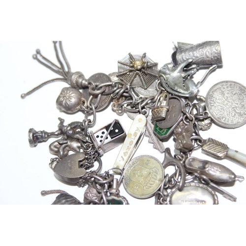 1243 - Silver charm bracelet with a large number of silver and white metal charms, approx 88.64g gross