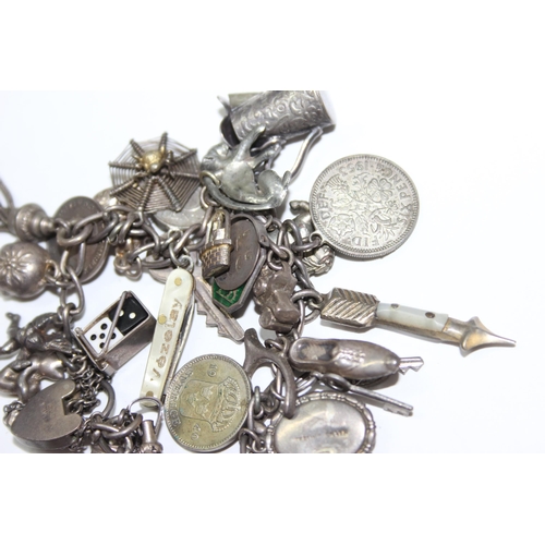 1243 - Silver charm bracelet with a large number of silver and white metal charms, approx 88.64g gross