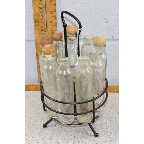 1844 - Circular oil bottle rack with wrought iron stand and wooden lids, some missing .