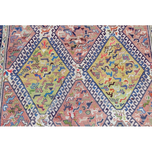 229b - A large multi-coloured flat weave rug with diamond shaped medallions, decorated with animals, approx... 