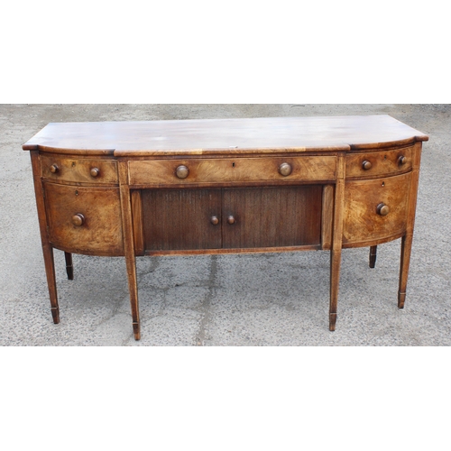 99A - An early 19th century tambour fronted mahogany sideboard of serpentine front with single drawer abov... 