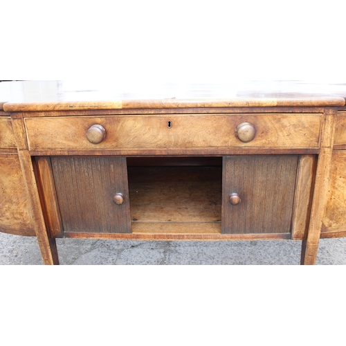 99A - An early 19th century tambour fronted mahogany sideboard of serpentine front with single drawer abov... 