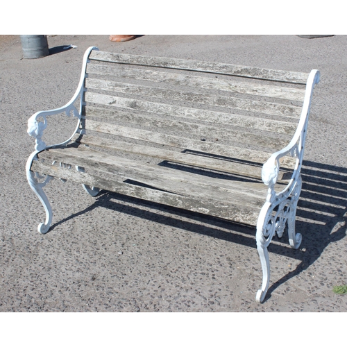 330 - A wooden slatted garden bench with white painted ends cast with lion masks