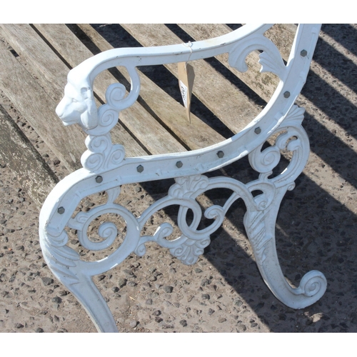 330 - A wooden slatted garden bench with white painted ends cast with lion masks