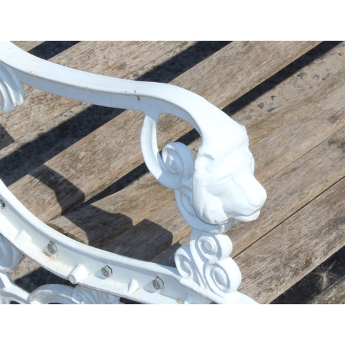 330 - A wooden slatted garden bench with white painted ends cast with lion masks