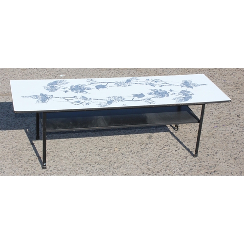 42 - A retro Formica topped coffee table with magazine rack, decorated with leaves `