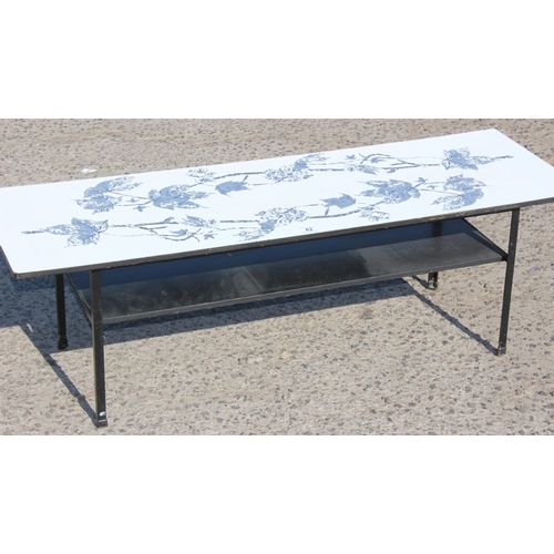 42 - A retro Formica topped coffee table with magazine rack, decorated with leaves `